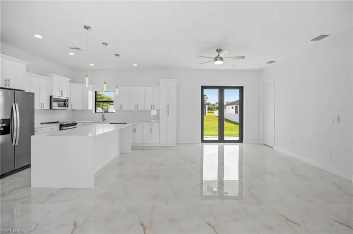 Kitchen with ceiling fan, stainless steel appliances, decorative light fixtures, light tile floors, and a center island