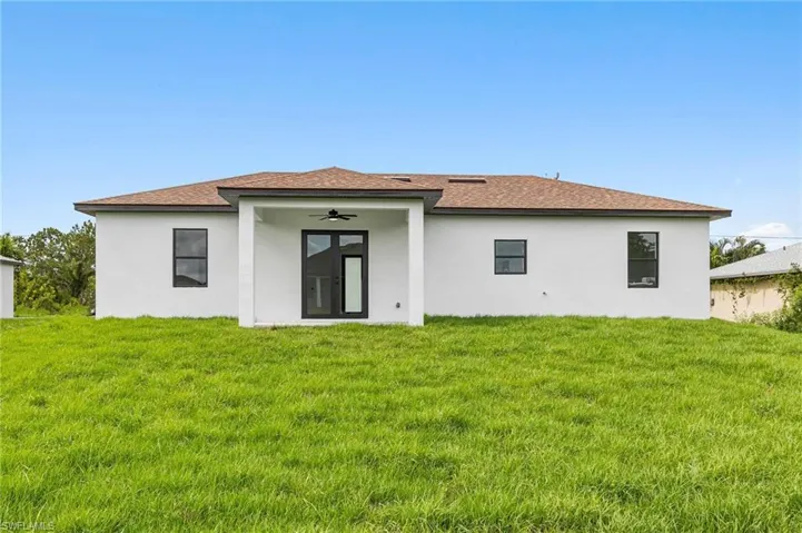 Rear view of property featuring a lawn and ceiling fan