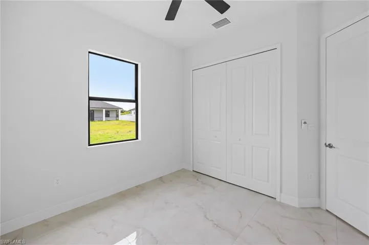 Unfurnished bedroom with a closet, light tile flooring, and ceiling fan