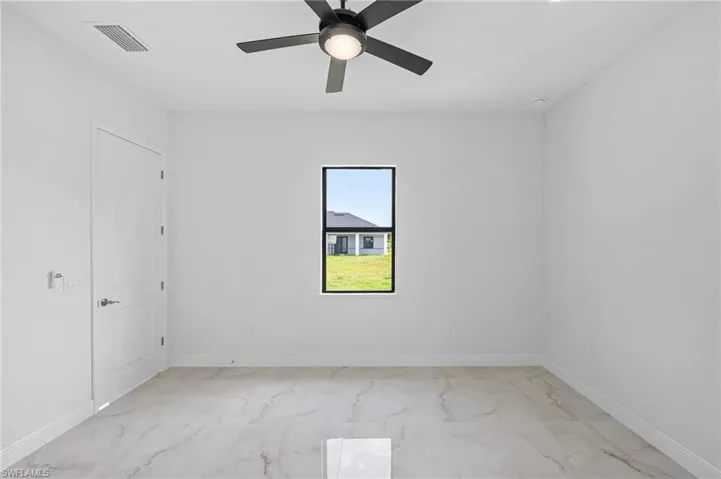 Spare room with ceiling fan and light tile floors
