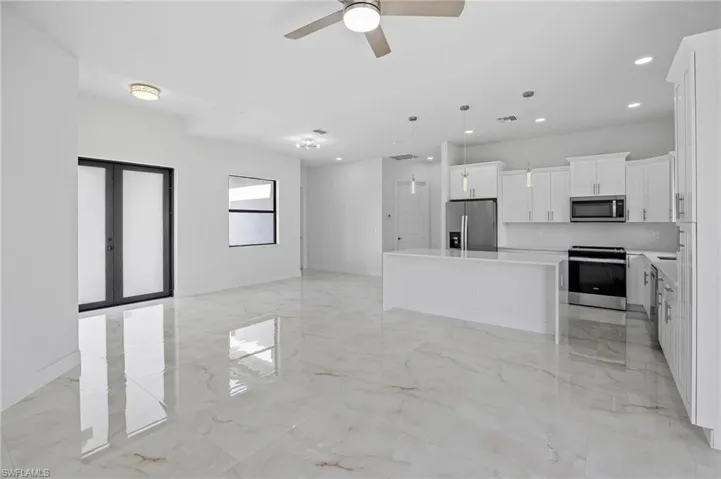 Kitchen with appliances with stainless steel finishes, light tile flooring, pendant lighting, and a kitchen island