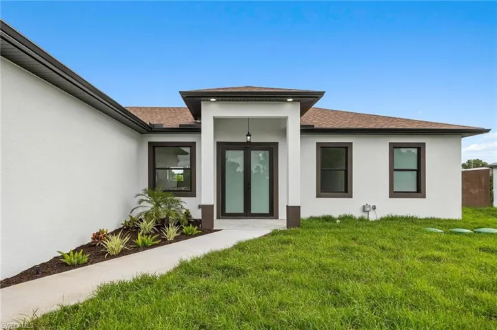Doorway to property featuring a lawn