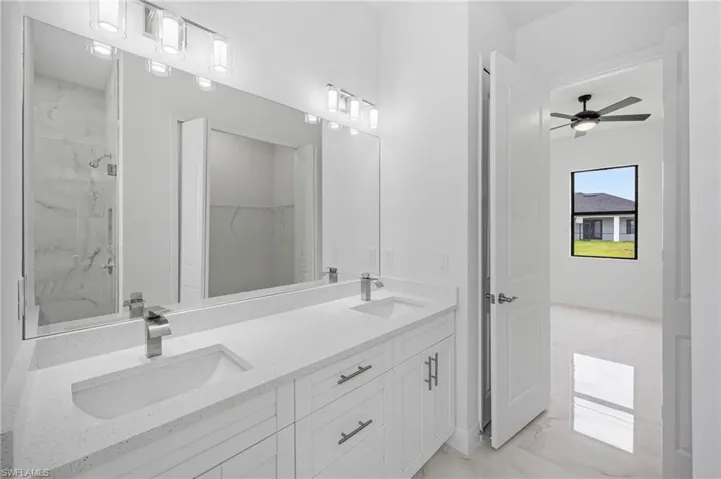 Bathroom featuring tile floors, ceiling fan, tiled shower, and double sink vanity