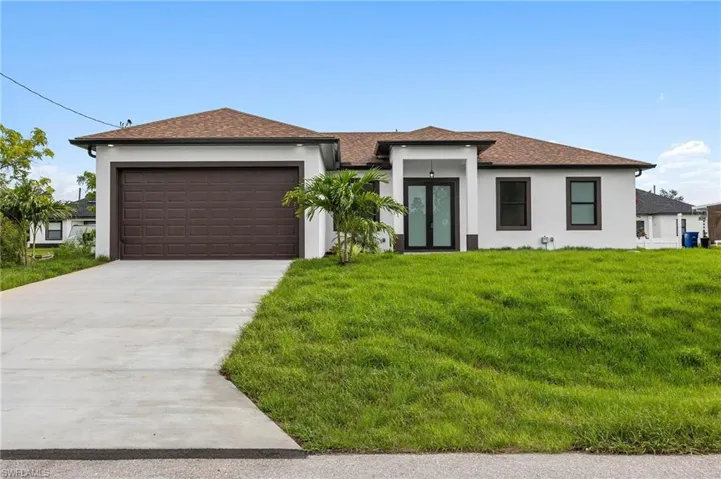 View of front of property featuring a front lawn and a garage