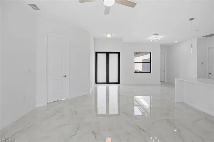 Empty room with ceiling fan and light tile floors