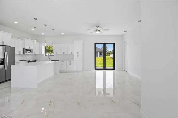 Kitchen featuring a healthy amount of sunlight, appliances with stainless steel finishes, a center island, and light tile floors