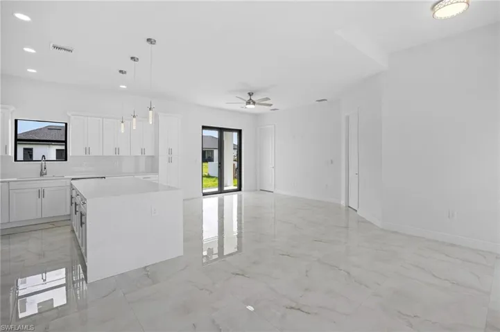 Kitchen with hanging light fixtures, white cabinets, ceiling fan, and light tile floors