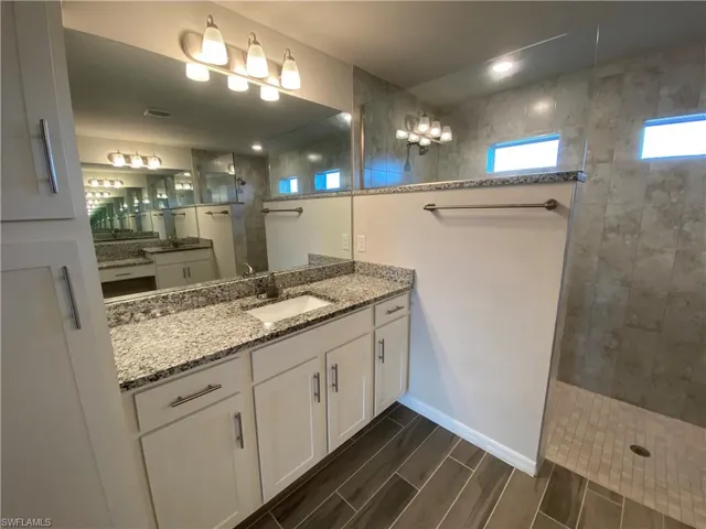 Bathroom with vanity, wood finish floors, and walk in shower