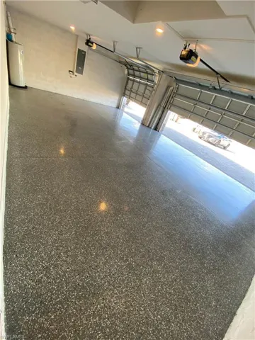 Garage with water heater, concrete block wall, and a garage door opener