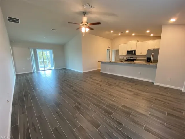 Unfurnished living room featuring lofted ceiling, wood finish floors, ceiling fan, and recessed lighting
