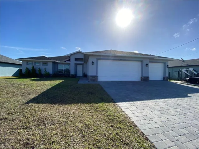 Ranch-style home with stone siding, stucco siding, decorative driveway, an attached garage, and a front yard