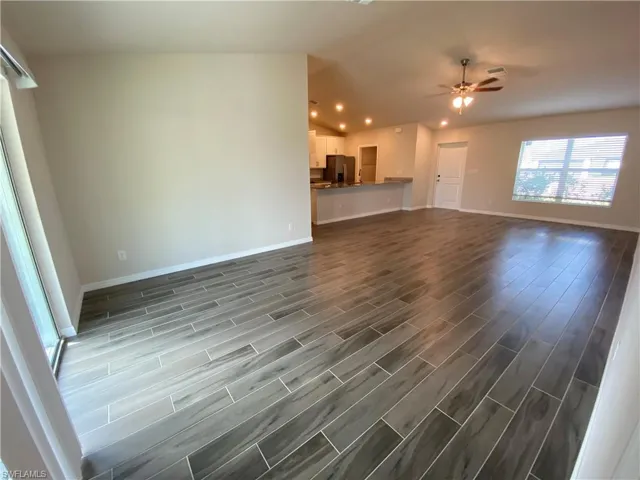 Unfurnished living room featuring wood finish floors, lofted ceiling, and ceiling fan