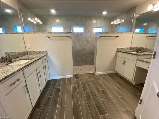 Bathroom with two vanities, wood finish floors, and a walk in shower
