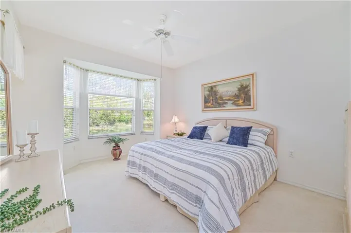 Bedroom with light colored carpet and a ceiling fan