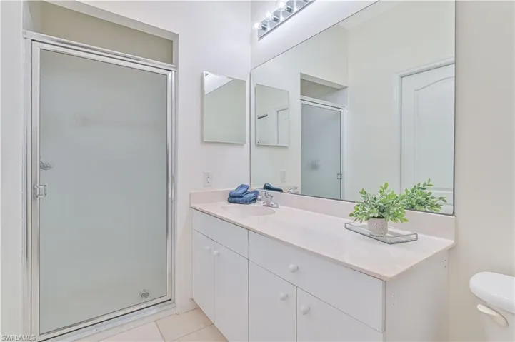 Full bathroom with a stall shower, vanity, and light tile patterned floors