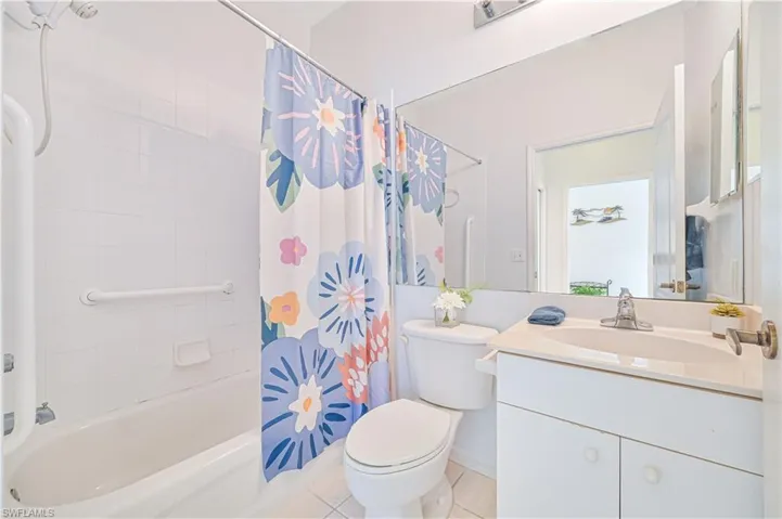 Full bathroom with vanity, shower / bath combination with curtain, and light tile patterned floors