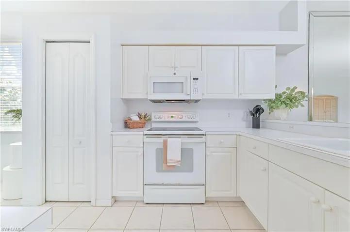 Kitchen with white appliances, light countertops, and white cabinetry