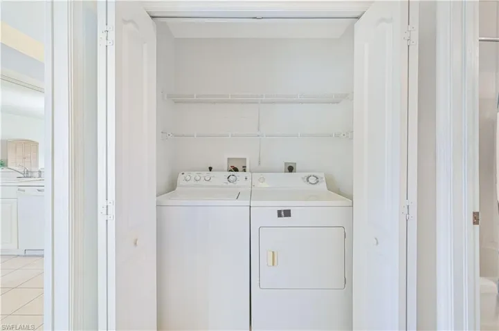 Laundry area with washer and dryer and light tile patterned floors