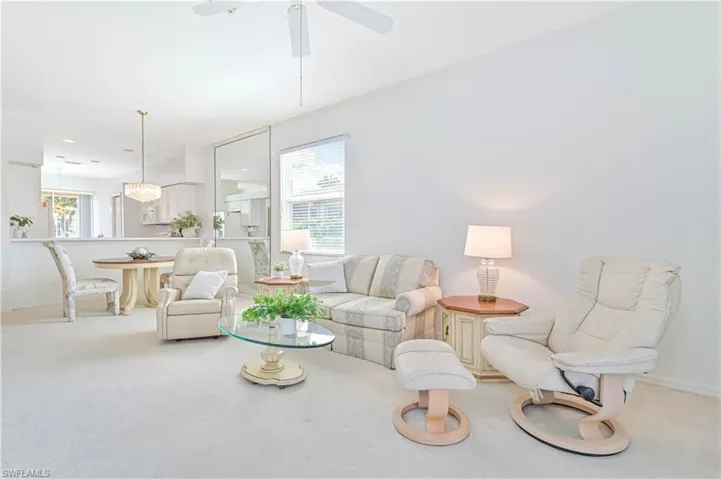 Carpeted living room featuring ceiling fan and baseboards