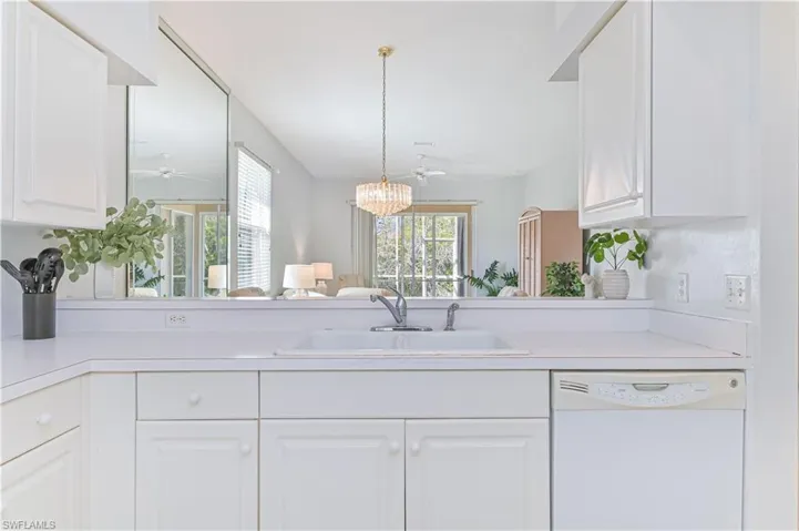 Kitchen with ceiling fan, dishwasher, light countertops, and white cabinets