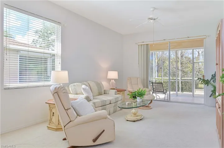 Living area with light colored carpet and a ceiling fan