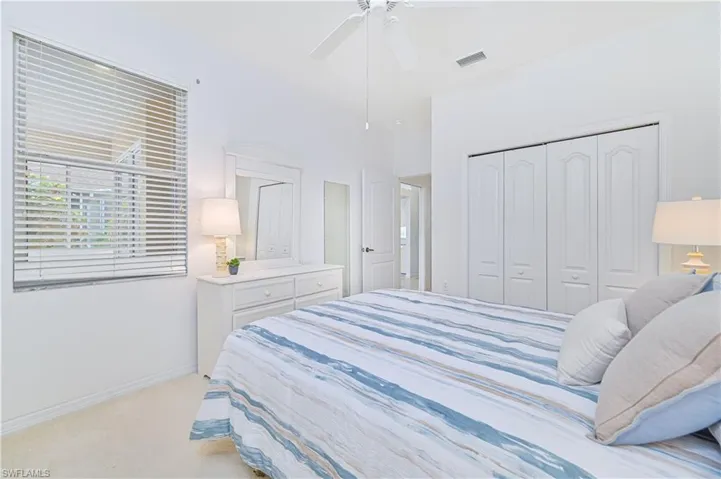 Bedroom with a ceiling fan, light colored carpet, and a closet