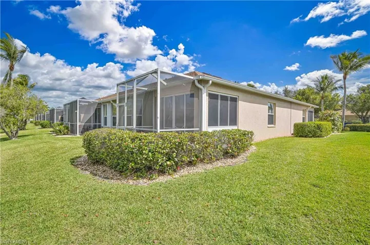 Rear view of property with a lawn, stucco siding, a sunroom, and glass enclosure