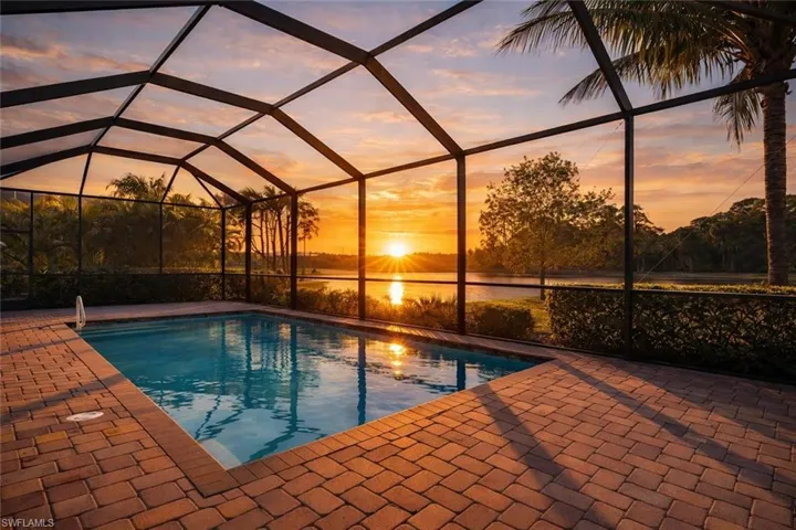 Pool at dusk with a water view, a lanai, a sunroom, and an outdoor pool