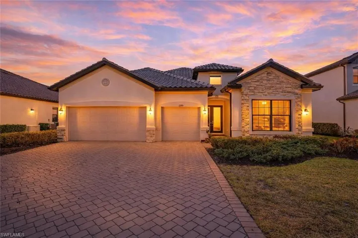 Mediterranean / spanish home featuring stone siding, stucco siding, an attached garage, driveway, and a front yard