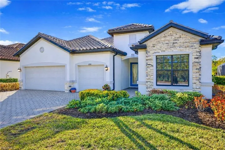 Mediterranean / spanish-style house featuring stone siding, stucco siding, decorative driveway, an attached garage, and a front lawn