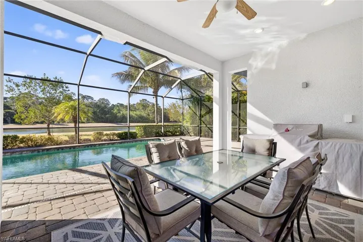 View of patio with glass enclosure, an outdoor pool, outdoor dining area, a sunroom, and ceiling fan