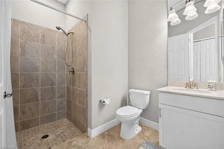 Full bath featuring a textured wall, a shower stall, and vanity