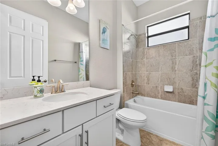 Bathroom with shower / bath combo, vanity, and a textured wall
