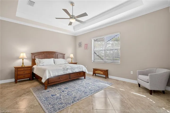 Bedroom with crown molding, a ceiling fan, and a tray ceiling