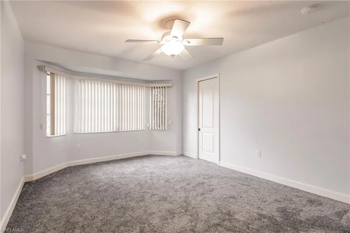 Carpeted empty room featuring ceiling fan