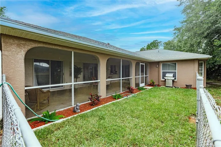 Back of house with a sunroom and a lawn