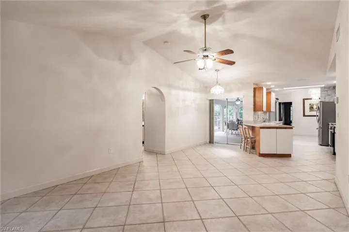 Kitchen with ceiling fan, light tile flooring, pendant lighting, lofted ceiling, and stainless steel refrigerator