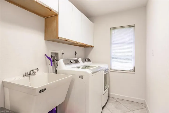 Washroom featuring cabinets, washing machine and clothes dryer, hookup for an electric dryer, sink, and light tile floors