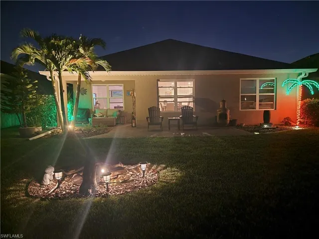 Back house at twilight featuring a yard and a patio