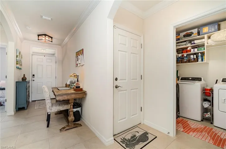 Tiled foyer with crown molding and designated laundry room with washer and dryer