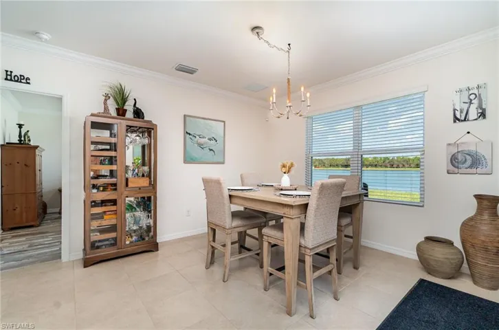 Tiled dining space with crown molding and a chandelier