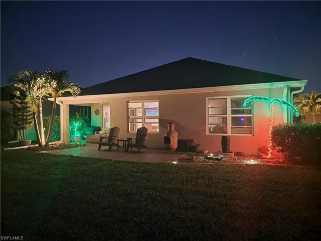 Back house at night with a yard and a patio area
