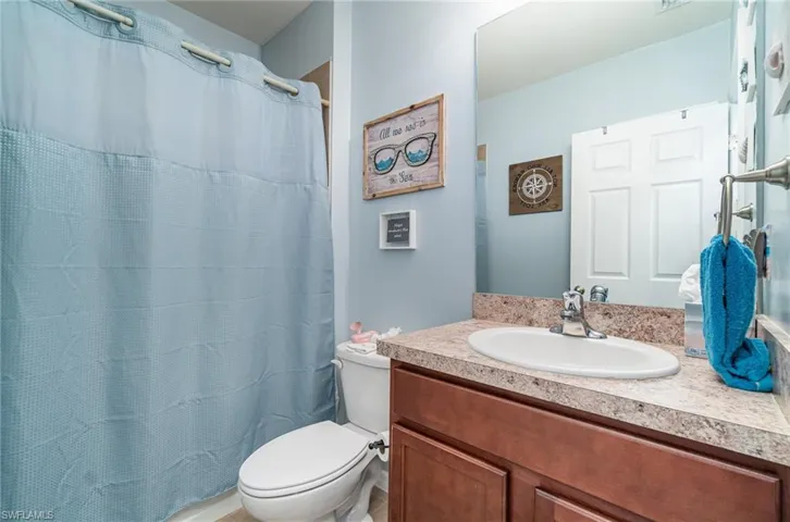 Bathroom with vanity, a shower with curtain, and toilet