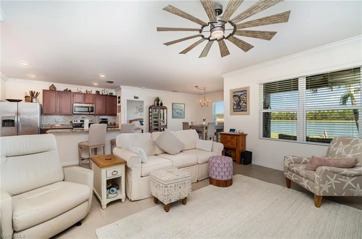 Tiled living room with crown molding and ceiling fan with notable chandelier