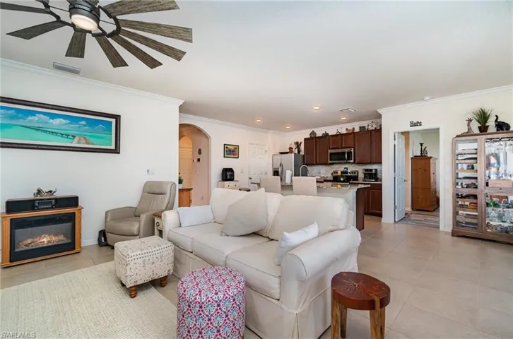 Living room with crown molding, ceiling fan, and light tile patterned floors