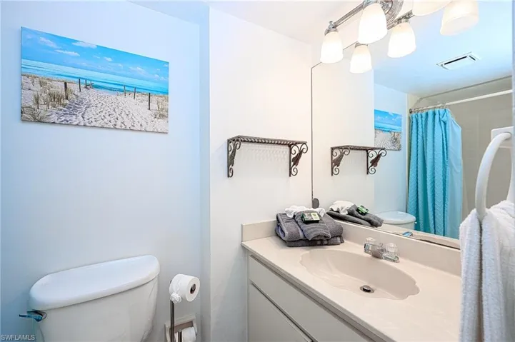 Bathroom featuring a shower with shower curtain, vanity, and toilet