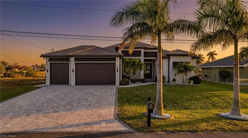 Prairie-style house with a lawn, an attached garage, decorative driveway, and a tile roof