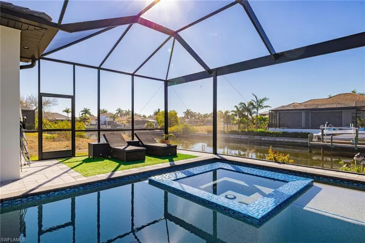 Combined pool / hot tub with a sunroom, a water view, a lanai, a patio, and a lawn