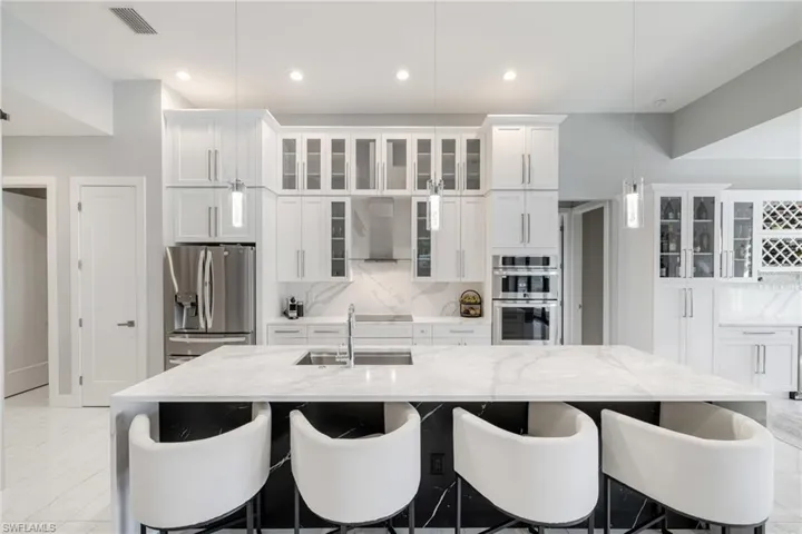 Kitchen featuring glass insert cabinets, white cabinets, and light stone countertops