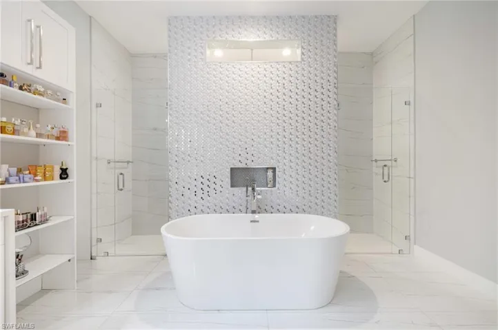 Full bathroom featuring tile walls, a marble finish shower, a soaking tub, and light marble finish floors
